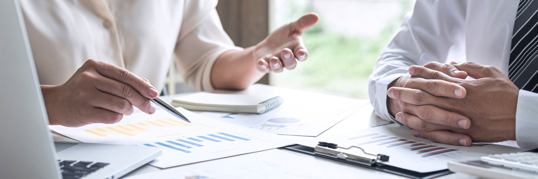 Two sets of hands at a business meeting with papers